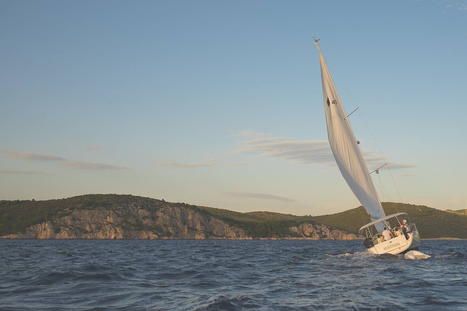 Yate a vela navegando cerca de la costa al atardecer